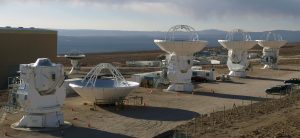 Photo of three completed and one incomplete ALMA antennas.