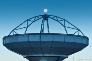 Photo of the full moon above an ALMA radio antenna.