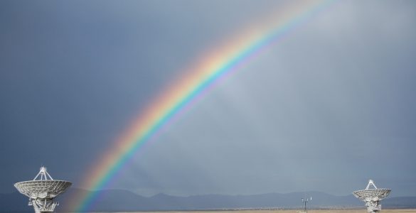 A photo of a rainbow over the VLA telescope in the desert.